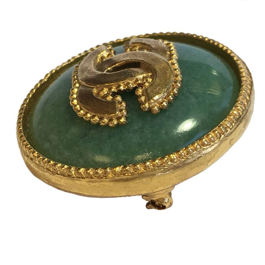 CHANEL round brooch in gilded metal and semi-precious jade color stone. A golden CC is in the center of the jewel.

Delivered in a Valois Vintage Paris Dustbag