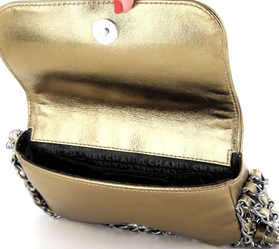 Collector! Small Chanel 'jewelry' flap bag in bronze gilded leather. On the flap There are chains on which are interlaced ribbons in leather. Blackened shiny silver metal hardware.
It is worn on the arm or the hand by a shoulder strap consisting of