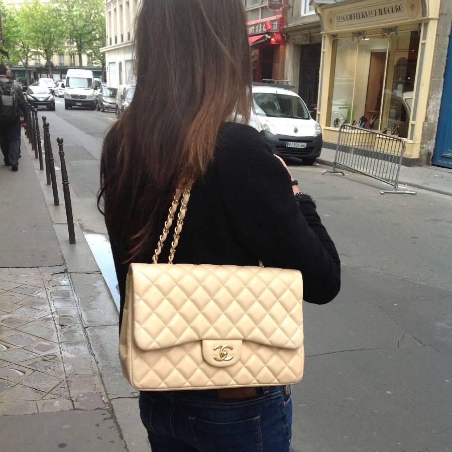 Superb Chanel Jumbo bag in beige quilted lamb leather. The hardware is in gilded metal. There is 1 back pocket and 2 inside pockets, one zipped. The chain is in gilded metal and beige leather, it has 2 shoulder straps that measure 60 cm each. 