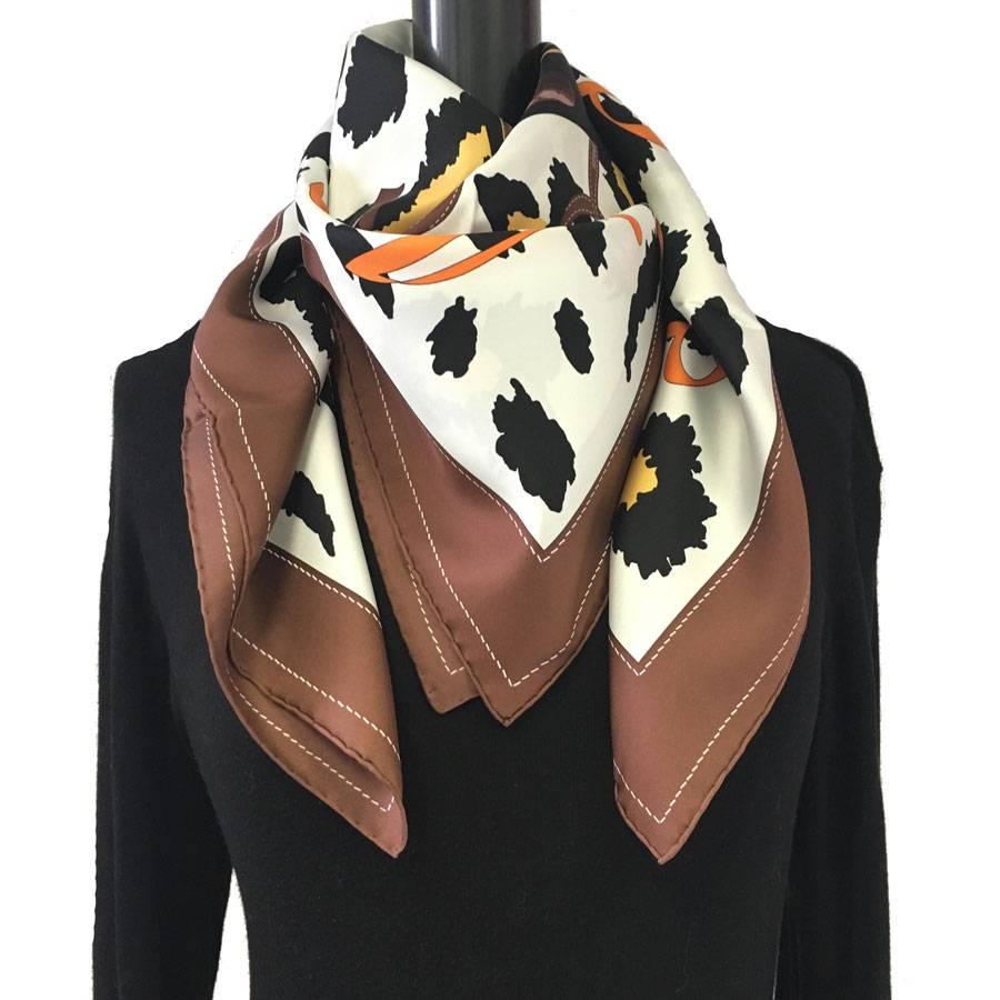 Hermès 'Monsieur, Madame' scarf in ivory silk and brown border, patterns :  symbols of the brand: leather goods, jewels, bags, perfumes.

Stamp S from private sales. 

Designed by: Bali Barret

Delivered in a Paris Vintage Valois pouch