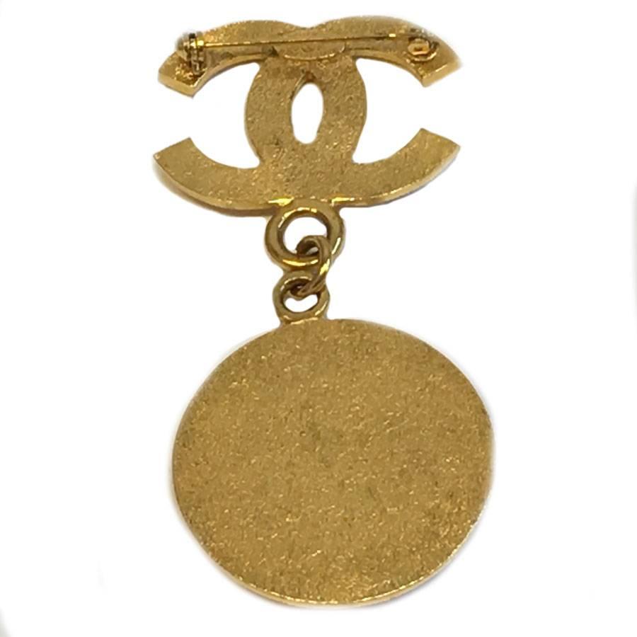 Beautiful Chanel CC brooch with a pendant medallion with CHANEL inscription in gilded metal.

Collection spring-summer 1996

Delivered in a Valois Vintage Paris dustbag