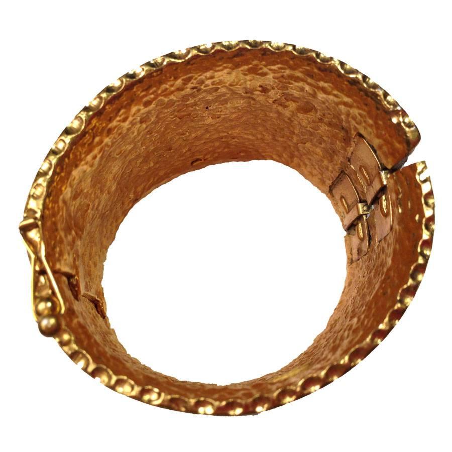 Exceptional CHANEL vintage gilt metal cuff bracelet. It is articulated by 2 springs and closes with 2 small clasps. The inside of the cuff is hammered, the outside is embellished with CC in relief.

Dimensions: wrist circumference: 20 cm 

 Will be