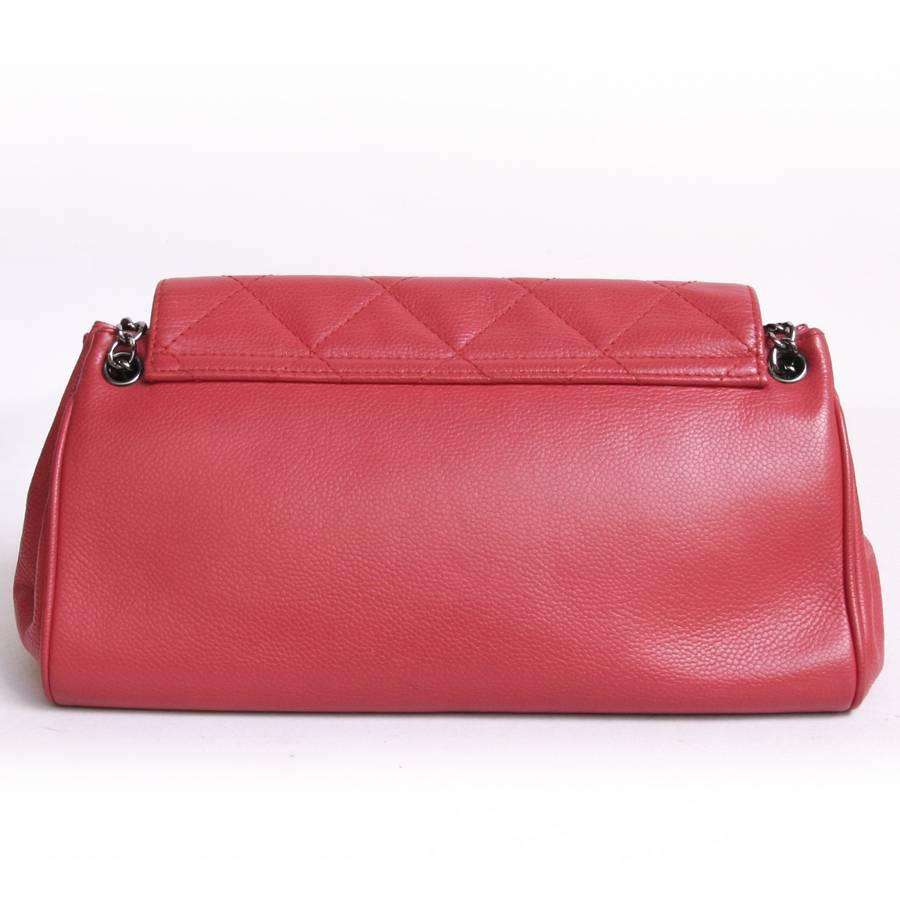 Chanel 'accordion' bag in red caviar leather. It has a rectangular trapezoidal shape, closed by a silver-plated rectangular buckle. The interior is lined with beige monogrammed canvas, a patch pocket, a zip pocket. 
Included : hologram 8837