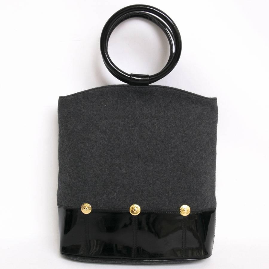 Givenchy handbag in gray felt. The handles and the bottom of the bag are in black patent. Zip closure. There are three fake Givenchy gold metal buttons on the front and back of the bag. The interior is in black leather. 

Dimensions : length of the
