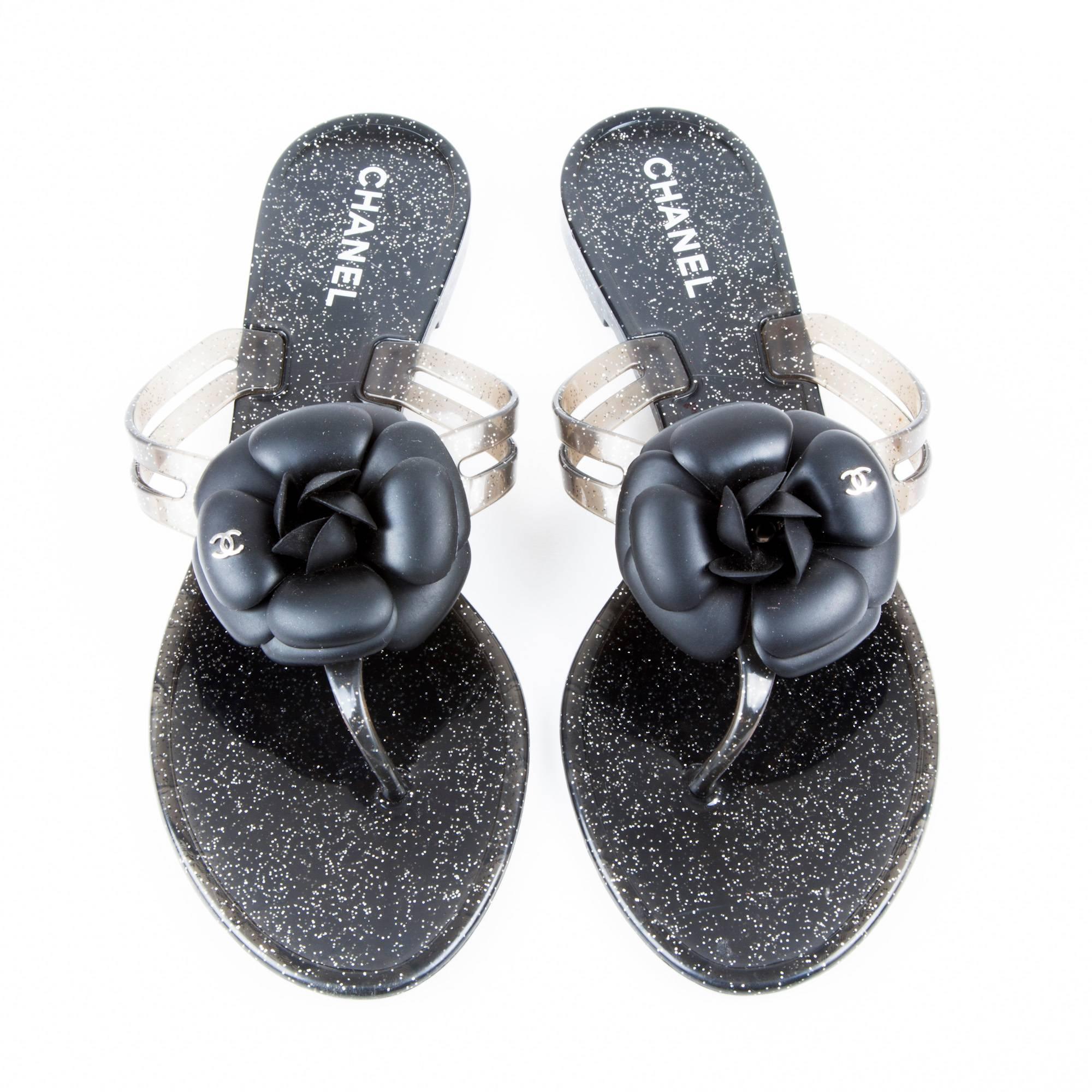 Chanel sandals in black and gray plastic with silver glitter inclusions.

Black camellia with a silver CC logo.

Length of the sole: 26 cm. In Very good condition.

Delivered in their Chanel box