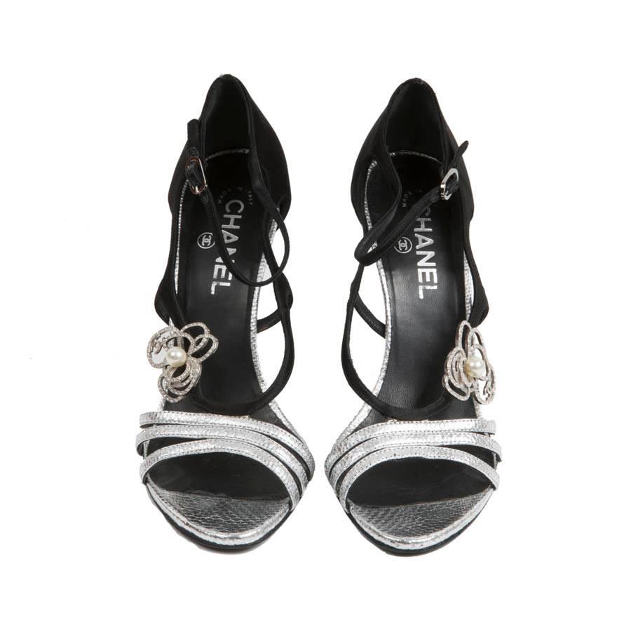 Chanel high sandals in silver python and black satin leather. Size 38.5. A rhinestone jewel with a pearl is in the center on each side. 

Heel height: 11 cm, insole length: 25.5 cm

Will be delivered in a Chanel box