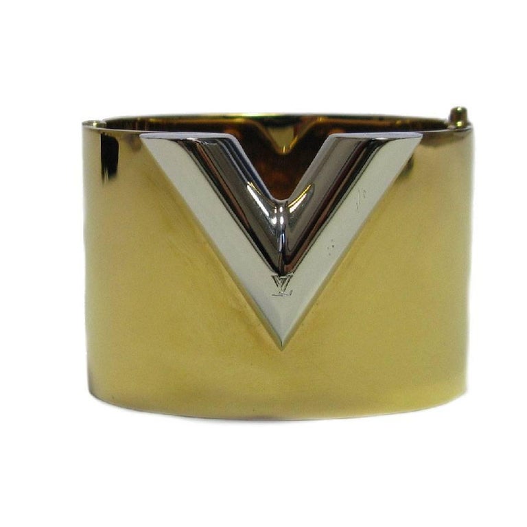 Beautiful Louis Vuitton cuff, model 'Essential V' in brass with a golden finish.

The initials LV are engraved on the front of the bracelet. Pusher clasp.

Made in Italy. Numbered: M61087

Dimensions: height: 4.2 cm, inside wrist circumference: 17