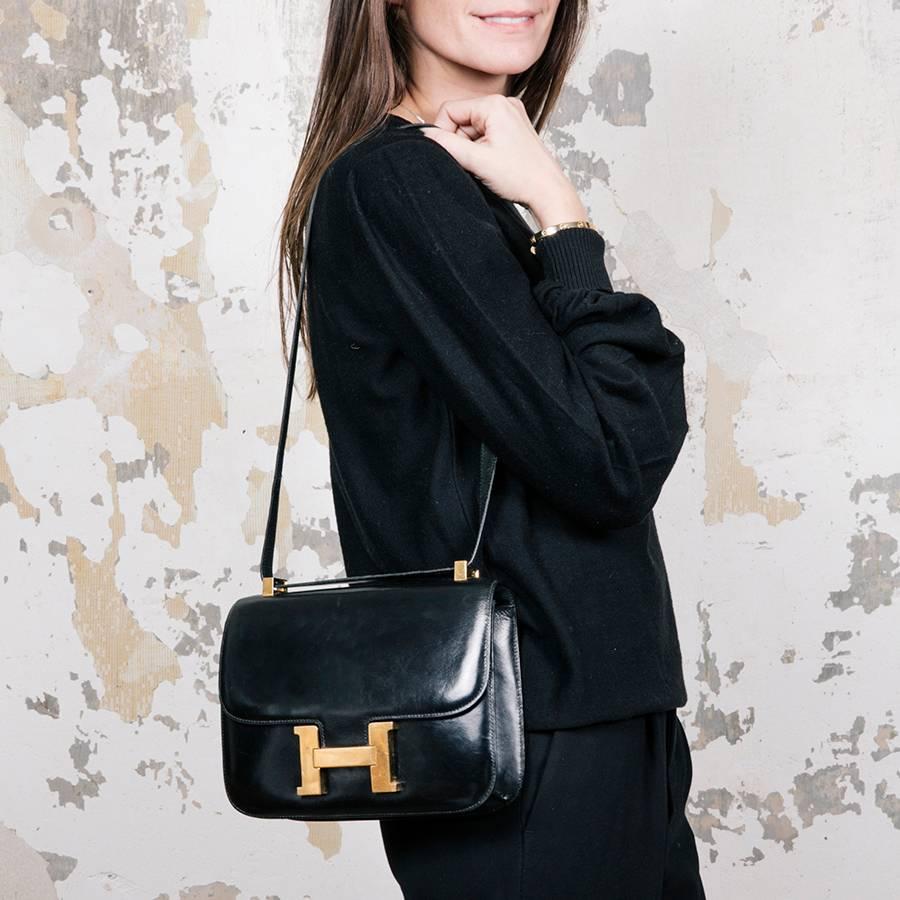 Hermès 'Constance' bag in black box leather. Gilded metal hardware. 

Made in France. Vintage, no hologram. In very good condition.

Dimensions : Length 23 cm, height 18 cm, depth 5 cm, shoulder strap 80 cm.

Will be delivered in its dust bag and