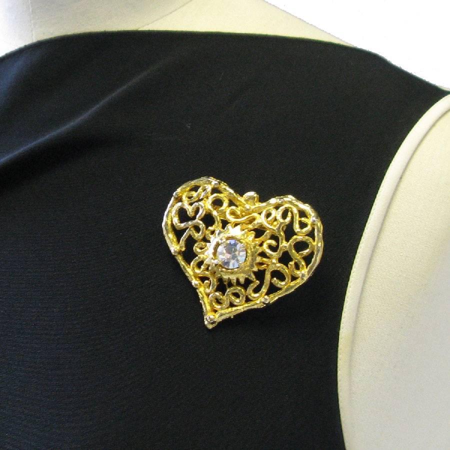 Christian Lacroix heart brooch in gilded metal set with a large white rhinestones in the center.

Vintage jewel.

The pellet of the brand is missing.

Dimensions: 5,8x5,5 cm

Will be delivered in a new, non-original dust bag
