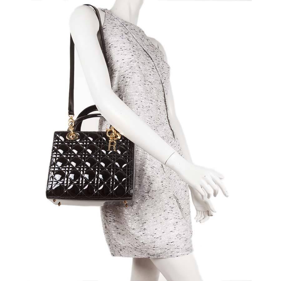 Christian Dior 'Lady Dior' bag in black quilted patent leather. Gilded metal hardware. Zip closure.

Worn by hand carried with two handles or on the shoulder with a removable shoulder strap The interior is made of fabric red with a zipped