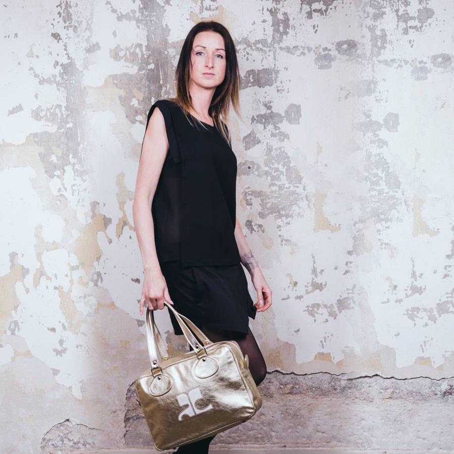 Courrèges bag in golden soft smooth lamb leather. Silver metal hardware. Double zipper. 

The interior is in matt silver fabric with many compartments including a zipped pocket. 

Made in Italy. Carry by hand or on the shoulder.

In very good