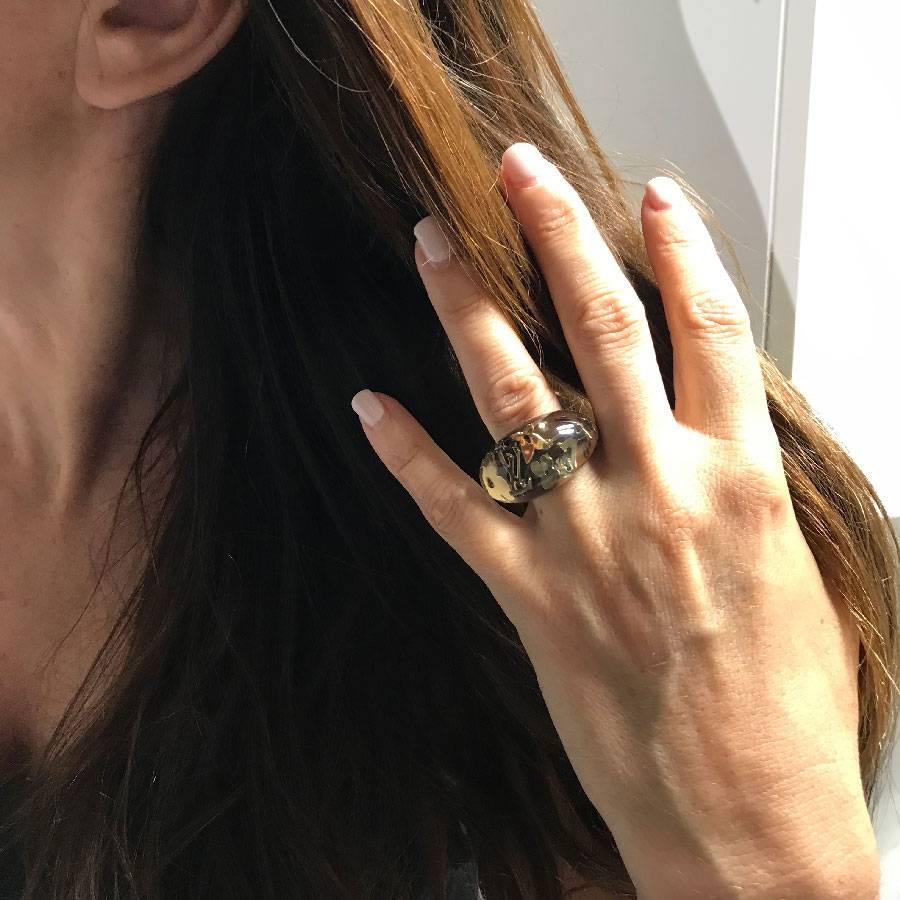 Louis Vuitton translucent ring revealing inclusions of L, V, shamrocks and flowers, symbols of the famous eponymous brand. The back of the ring is brown chocolate.

its condition is impeccable, no signs of wear to report. Size 51FR

Will be