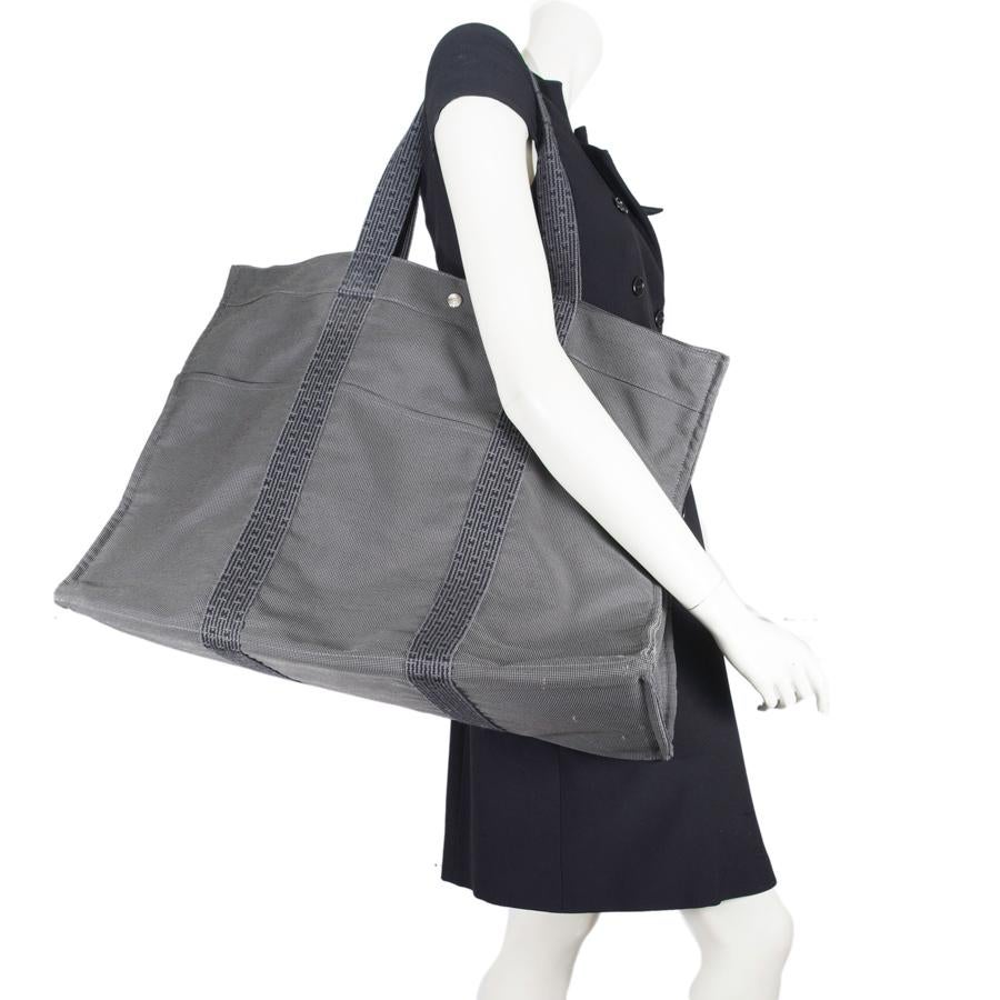 Ideal for a few days getaway. Weekender bag from Maison Hermès in gray canvas. Snap closure and zip. Inside, it has 4 patch pockets. 3 patch pockets at the front of the bag and at the back. In very good shape. Slight wear on the corners under the