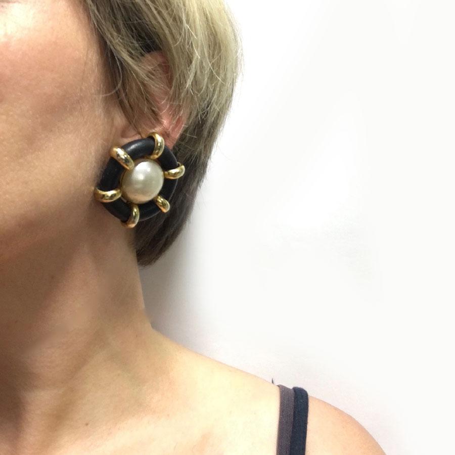 Chanel clip-on earrings in black faux leather, gold metal and mother-of-pearl in the center.

Made in France, 2002 collection.

Jewel in good condition. Splinters on the pearls and some traces of wear on the black leather (see photos)

Dimensions: