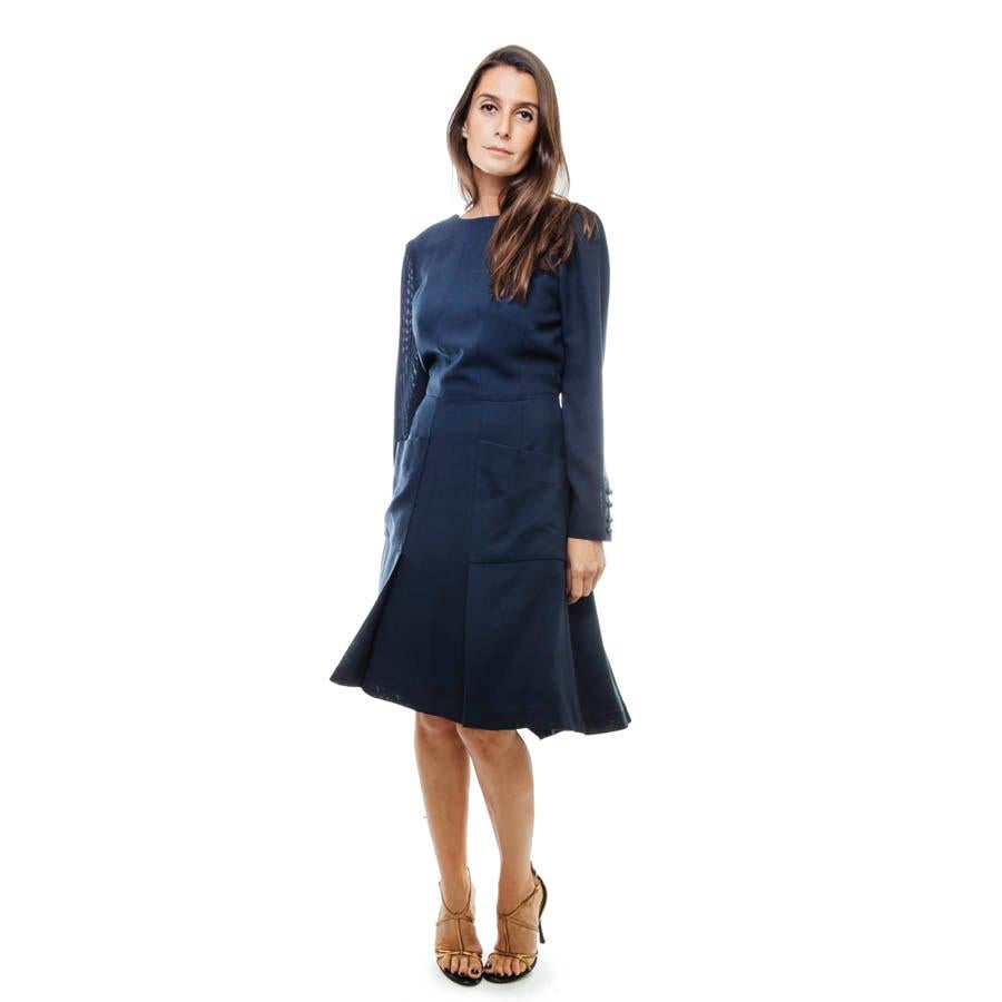 Chanel wrap dress in navy blue fabric with 2 wide Chanel blue pockets. It corresponds to a size 38/40 (no size and material label). It closed at the front with invisible hooks. 

Along the wrists 4 golden 'CC' buttons pearl shaped . 

It is lined