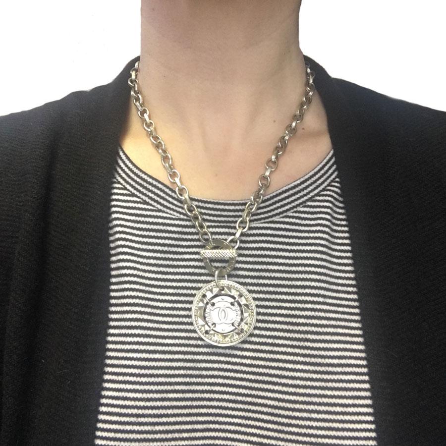 Trendy! CHANEL necklace in pale gilt metal. Round medal with a double C in the center. The toggle clasp is worn on the front of the collar.
Inscription CHANEL PARIS on the ring as well as on a part of the medal.

Brand on the back of the medal.