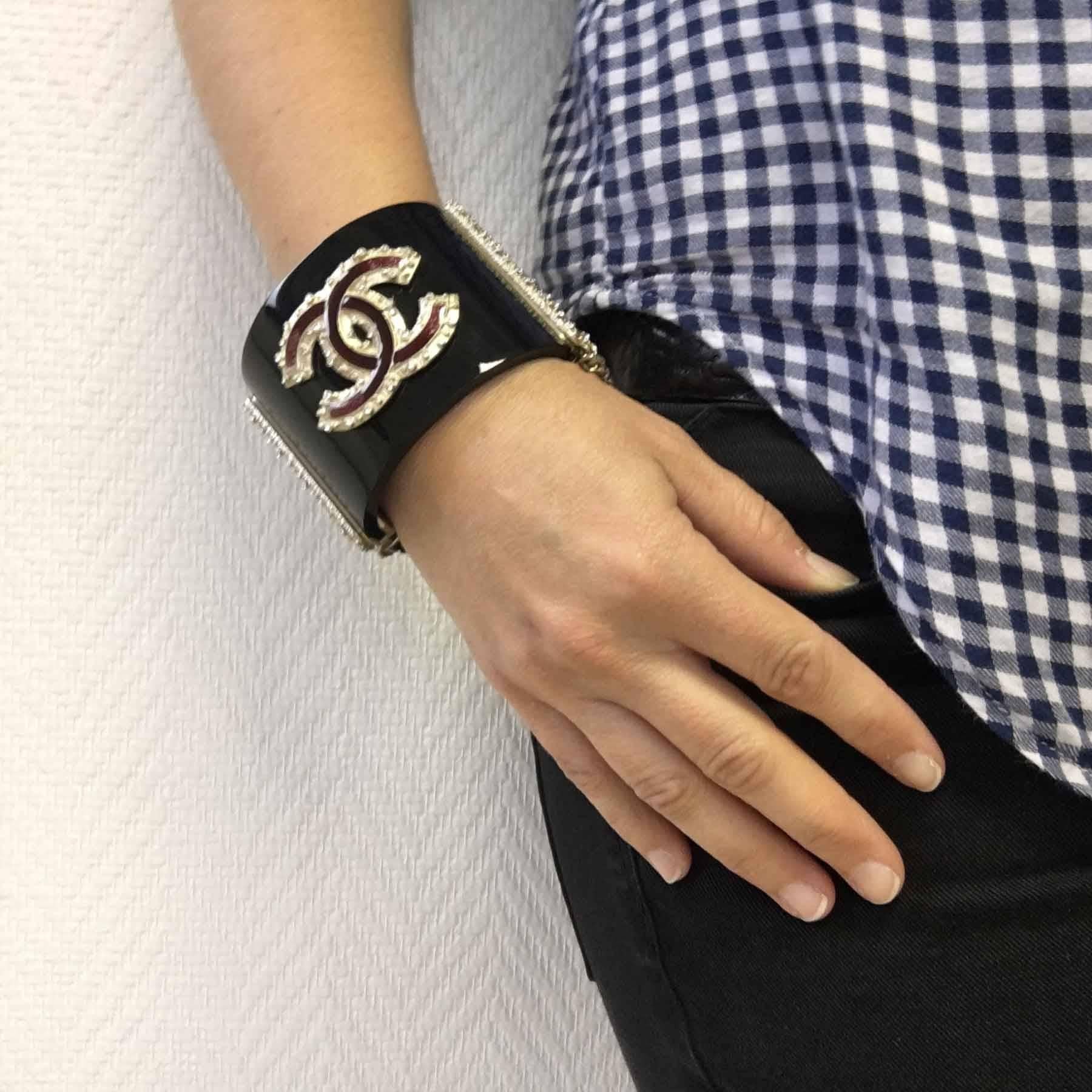 Black Chanel cuff, gold-tone metallic CC and burgundy resin set with small crystals. Safety chain.

Opens by a Chanel push button. Spring Collection 2011.

Wrist size 22.5 cm

Delivered in a Valois Vintage Paris dustbag.
