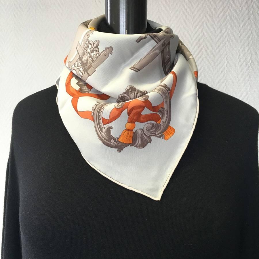 Hermès 'Ferronnerie' small scarf in taupe, gray, yellow and orange silk. In very good shape. A small stain on the gray background. The roulotté is impeccable.

Designed by: Caty Latham.

Material label present. Stamp S from private