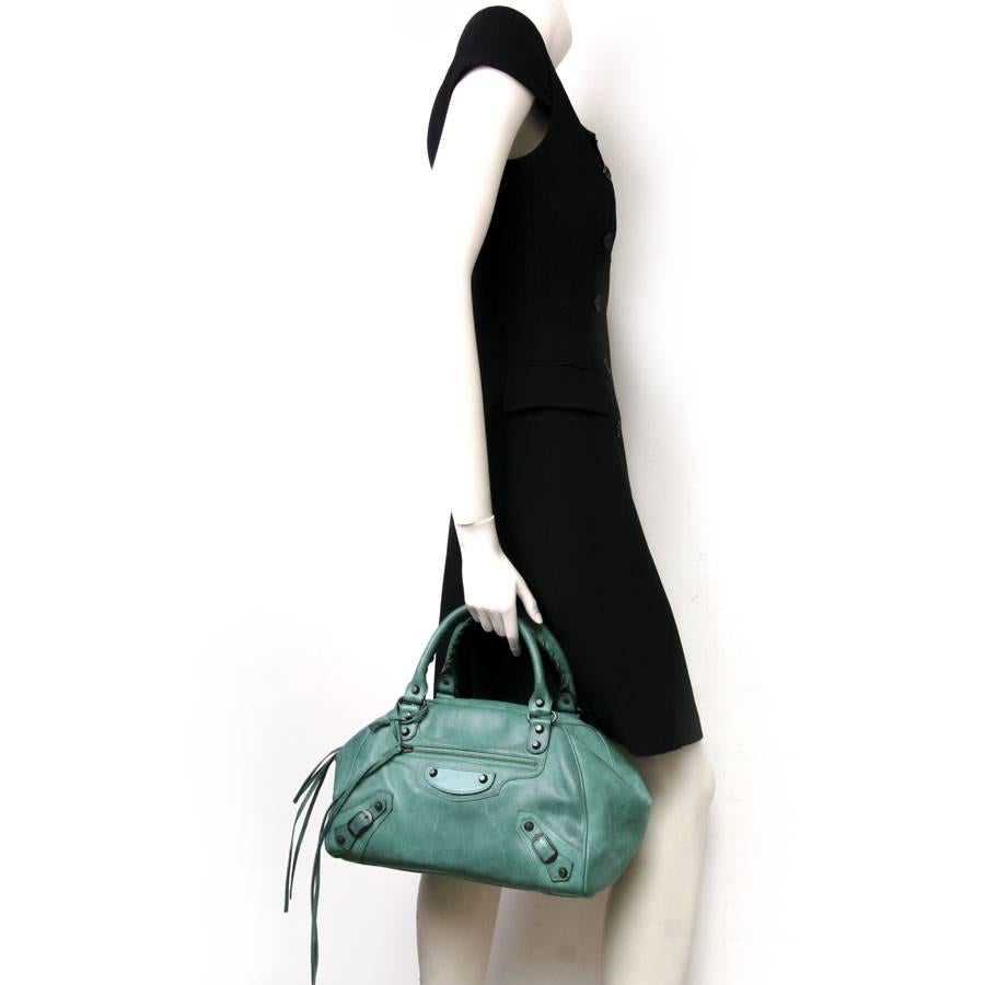 Balenciaga green leather bag with aged brass hardware. Very original closure by a zipper and two magnets folding and masking the latter. 
Impeccable interior. 
Light spots scattered on the bag (front, back, top). Slight lighter marks on the front of