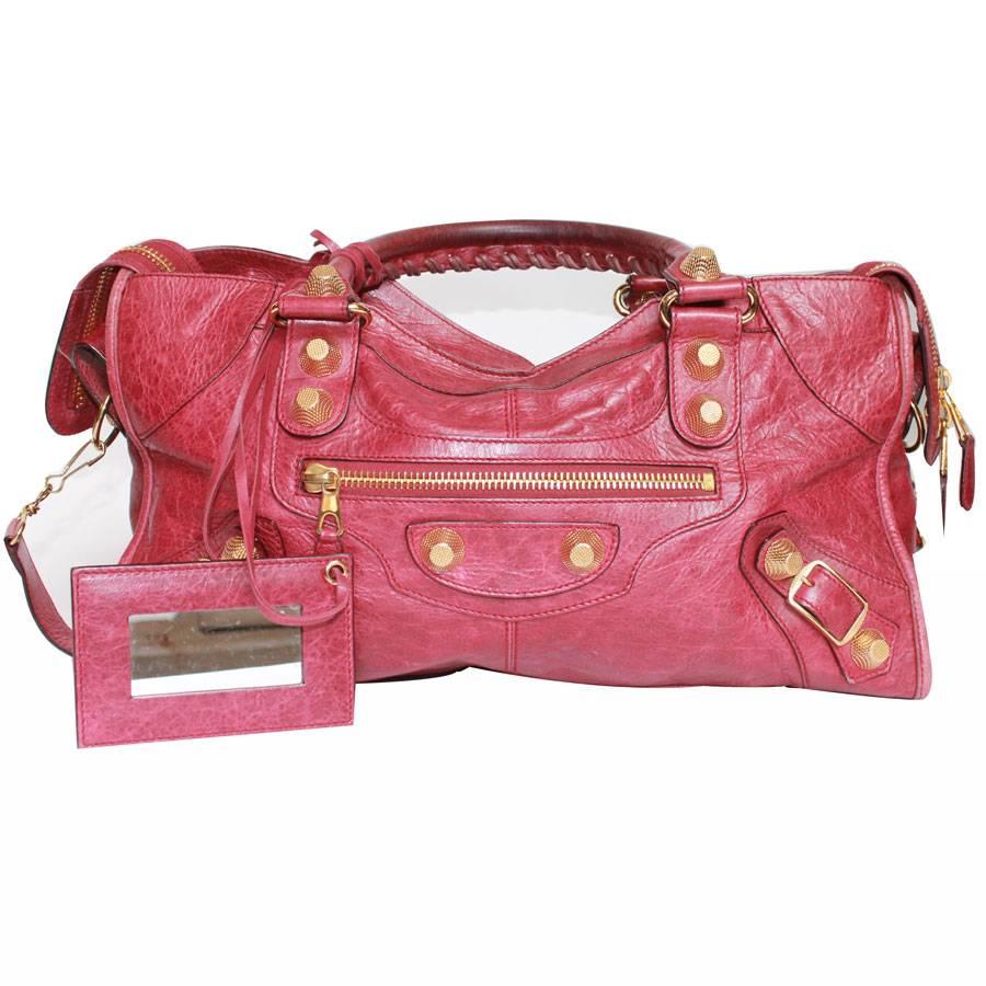 Balenciaga 'City' bag in red aged leather. Gold metal hardware. Zip closure.

Worn by hand with two handles and on the shoulder with a removable shoulder strap. The interior is in black canvas with a large zipped pocket and a mirror with red leather