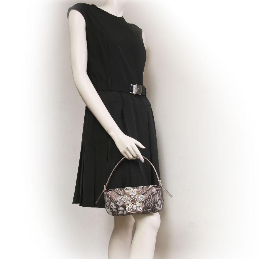 Mini Valentino evening bag in bronze satin and lace. Closing by pressure. The clasp is shaped like flowers with fancy stones. 

Worn by hand or on shoulder with an adjustable and removable handle in golden leather.

The interior is in bronze satin
