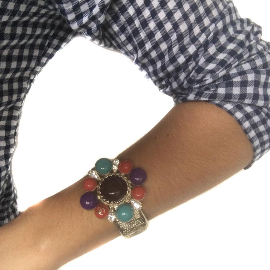 CHANEL rigid bracelet in hammered pale gold metal. Jewel in multicolored resin (turquoise, brick, purple and brown), 4 rhinestones and golden CC. The inside of the bracelet is in black glittery resin.
In very good condition. Made in