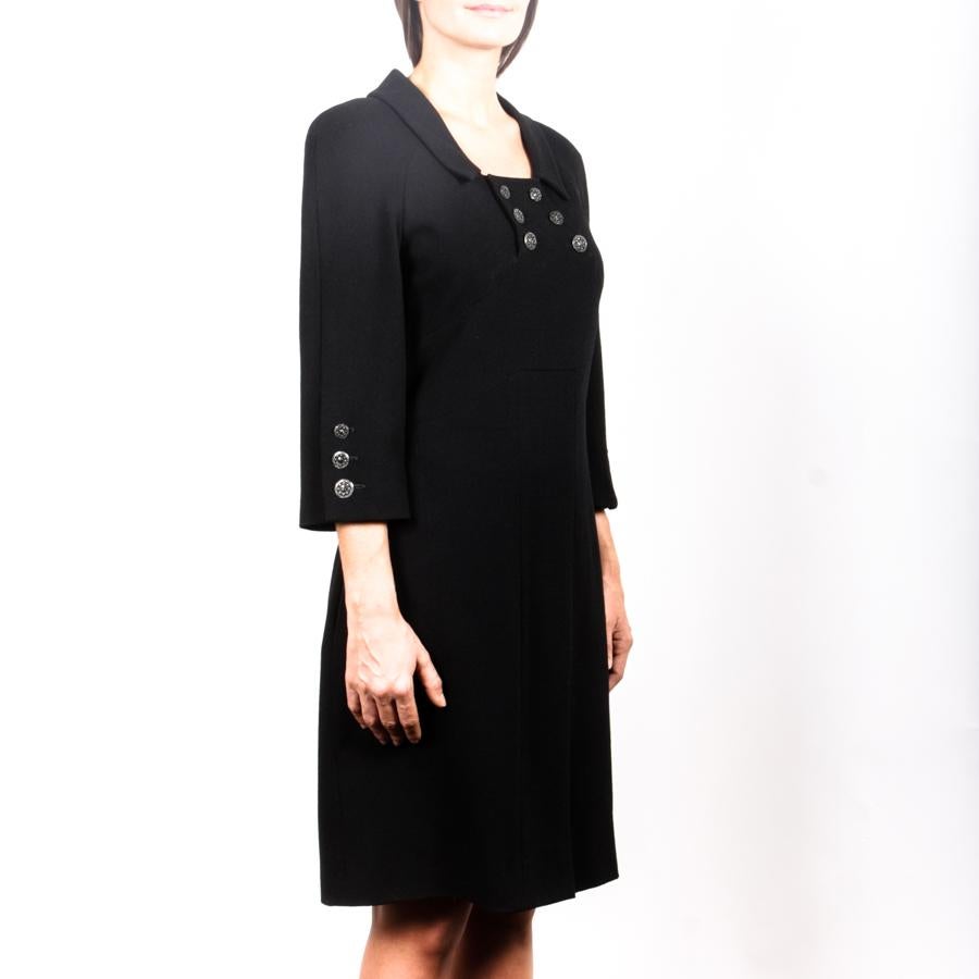 Chanel dress in black wool with cutouts and 2 vertical pockets on the sides.
It is embellished with 6 buttons at the front collar in black metal.
It closes with a zipper on the back. The sleeves are 3/4. Size 42FR
The lining is in black silk with