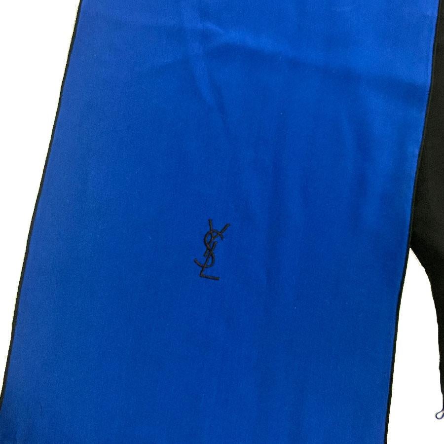 Very beautiful Yves Saint Laurent vintage scarf in black silk on one side and electric blue on the other. The initials YSL are embroidered in black on blue. It is embellished with fine blue fringes.
Made in France. 
It can be worn on a dress or on a