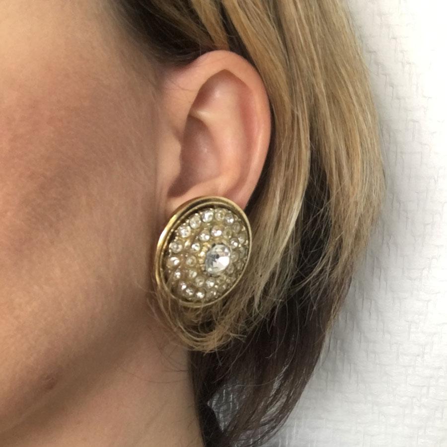unsigned round clip-on earrings in gilt metal and rhinestones

This fancy pair is unbranded. The color of the metal is a little passed on all loops.
In good condition.
Dimension is: 3.2 cm in diameter

They will be delivered in a new, non-original
