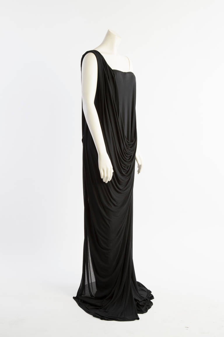 A stunning example of Alexander McQueens design aesthetic , this well constructed modern take in a grecian goddess gown has a simplistic silhouette due to the masterful draping of fabric from the side across the front and over the shoulder. This
