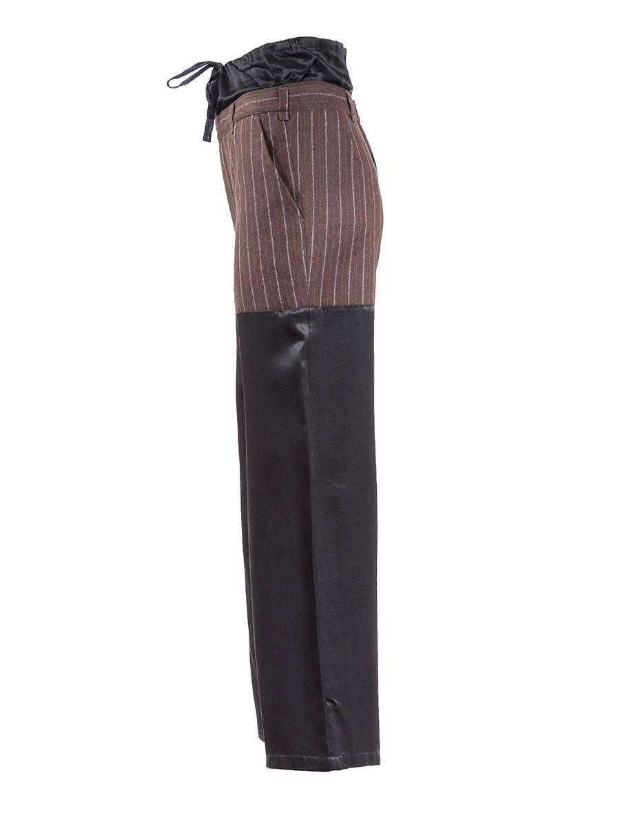 Maison Martin Margiela 20th Century Artisanal Patched Trousers featuring a brown vertical striped wool upper panel with black viscose legs. Has an extended black silk drawstring waistband, two front pockets, belt loops, and a zip fly fastening.

