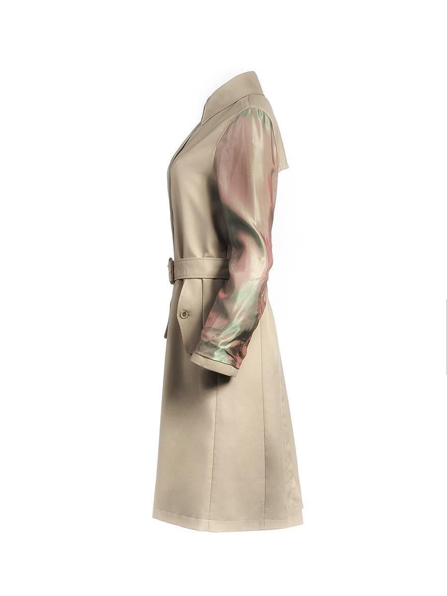 Iridescent sleeve coat from MAISON MARTIN MARGIELA. This 20th century tan polyester and wool blend coat features a folded collar, concealed button down front, and two button flap front pockets. Has green and purple iridescent long sleeves with thin