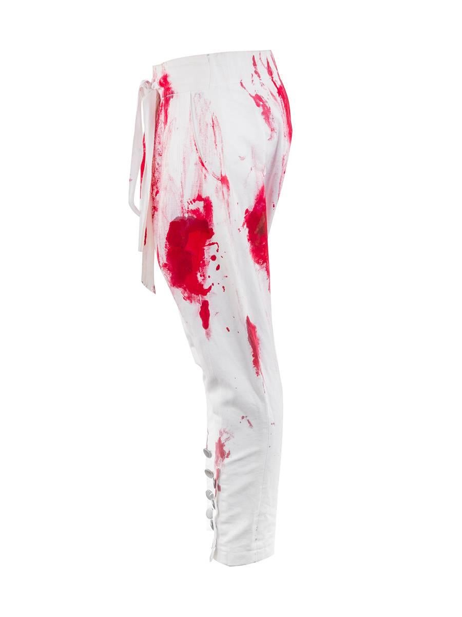 2010 Couture Josephus Thimister Moujik Trousers featuring a drop crotch waist with red paint stains. Has button tapered ankles, elastic back waistband, drawstring front waistband, and a folded front seam. New with Tag.
