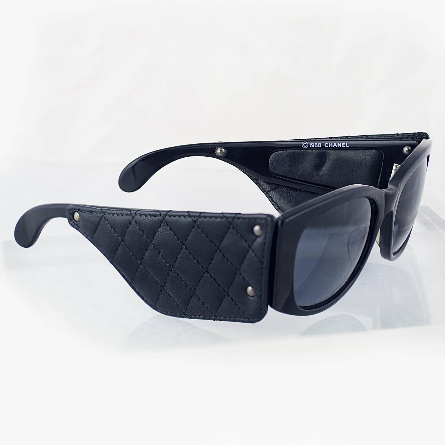A pair of exceptionally rare 1988 Chanel sunglasses with black quilted leather to the arms. 
A famous and sought after style! This style were used for the hugely famous Chanel 80's advertising campaign.
With original box and dust cover. 
In a very
