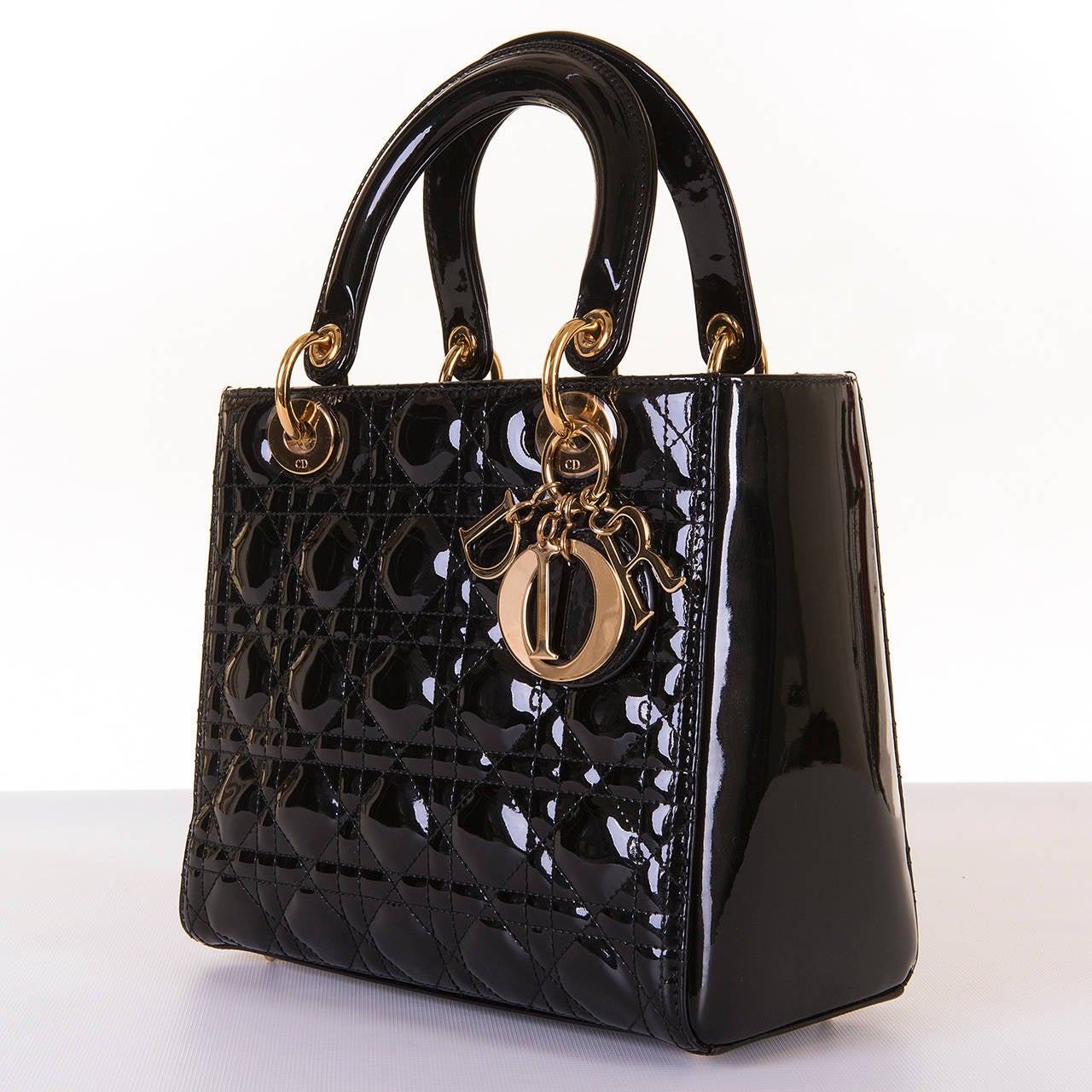 The much sought after medium size 'Lady Dior' handbag by Christian Dior, finished in Black quilted patent leather with gold tone hardware. This bag is in pristine 'new' condition and comes with it's Dior dust-sack.