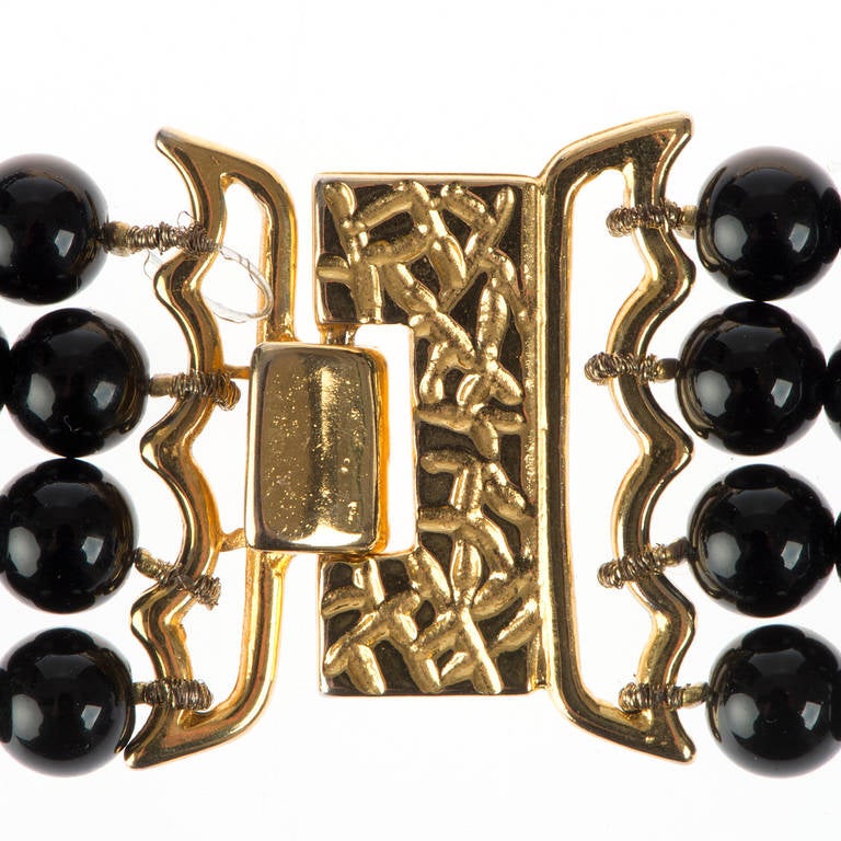 This signature piece by Rita Frasaone of Florence, Italy, is a 'Timeless' jewel that will complement many different looks and outfits. Four rows of black glass pearls are complemented with the gilt-metal inset with varigated brown enamel panels.