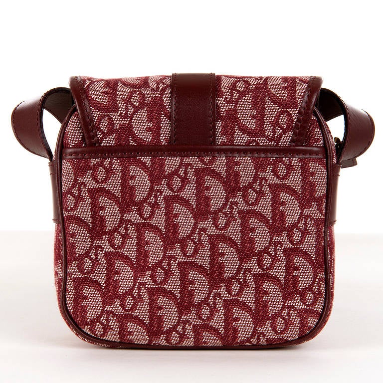 A super, cross-body or shoulder bag, by Christian Dior, Paris. Finished in Burgundy, Dior 'logo', printed toile with matching leather trim and goldtone fittings.There is an envelope pocket under the opening flap and inside there is a zipped pocket