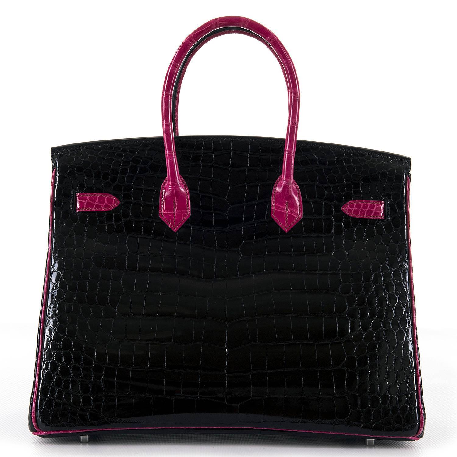 An Extremely Rare Hermes 35cm Special Order 'HSS' Shiny Crocodile Birkin Bag. In absolutely pristine condition, the bag is finished in Black with Fuchsia Pink trim, accented with silver Palladium hardware.Considered to be the ultimate luxury