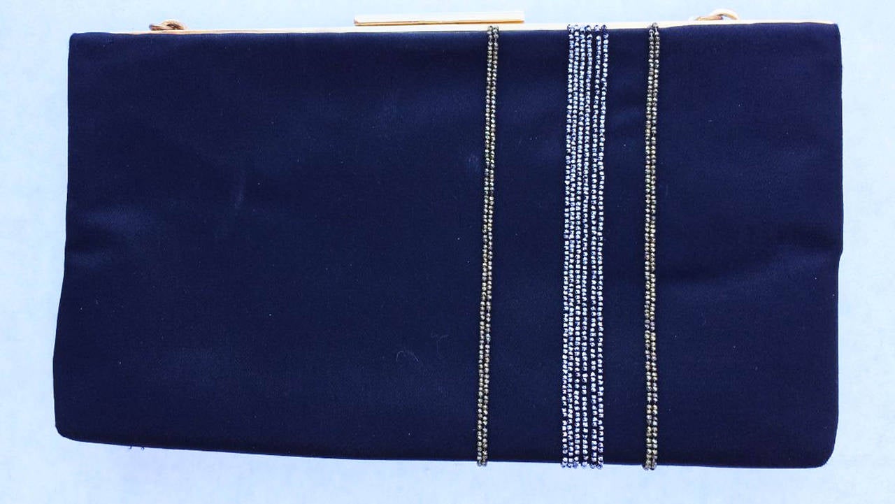 A fine and rare vintage Pierre Cardin couture handbag. Authentic black silk satin 'envelope' clutch features steel cut metal beading and gilt gold metal drop shoulder strap and frame. Item features a hidden snap closure and vanity mirror. Pristine