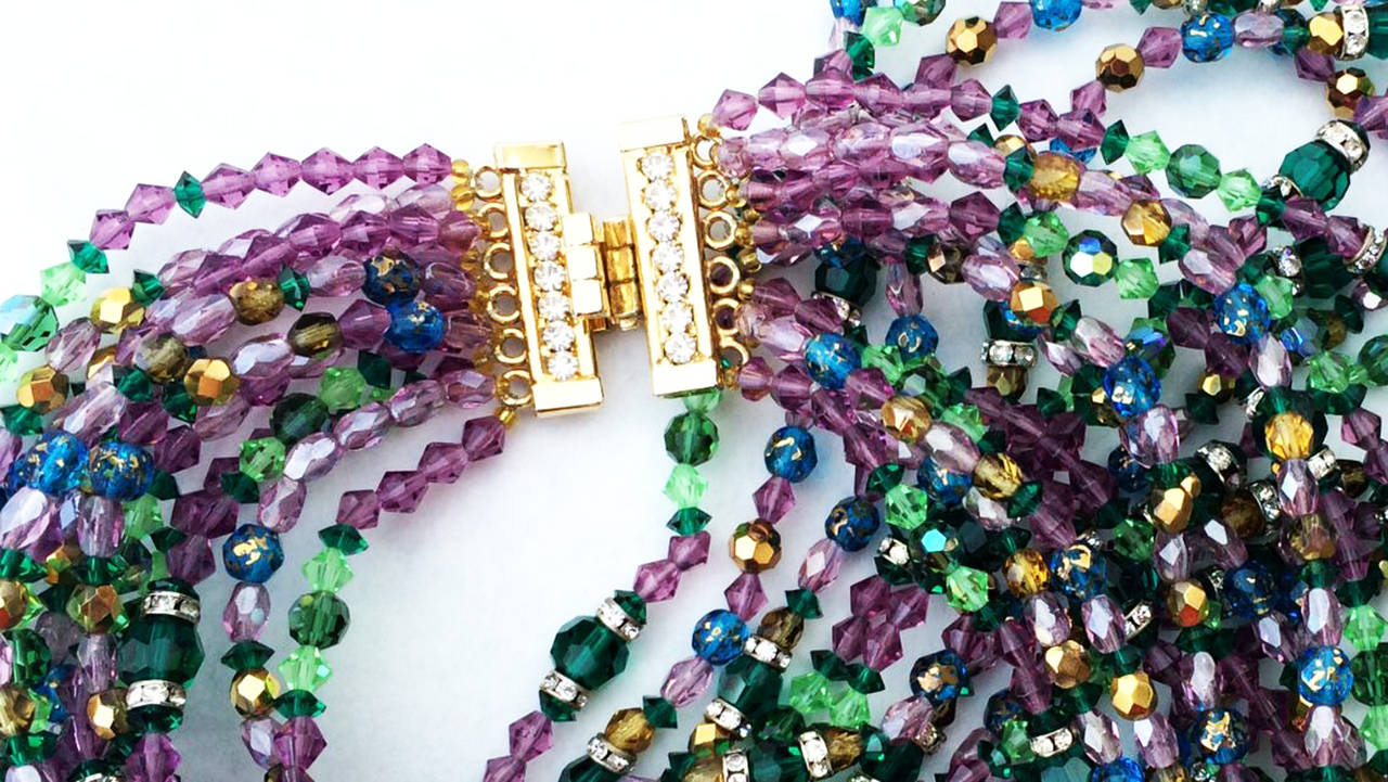 A fine and rare vintage William de Lillo torsade necklace. Signed gilt metal eleven strand item features multi-color aurora borealis faceted crystal glass and rondelle beads with a 'jeweled' crystal covered gilt metal hidden push clasp closure.