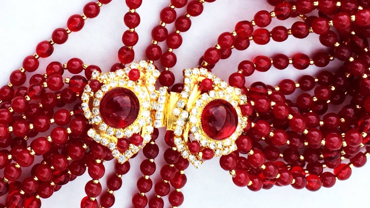 A fine and rare vintage William de Lillo multi-strand torsade necklace. Signed gilt metal twelve strand item features ruby red glass and gilt gold beads and a 'jeweled' crystal covered gilt metal hidden push clasp closure. Non-produced one-off