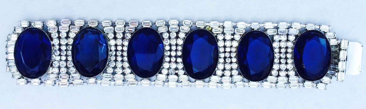 A fine and rare vintage William de Lillo faux diamond and sapphire bracelet. Signed rhodium plated metal item in the art deco manner features Swarovski crystals and large vibrant glass 