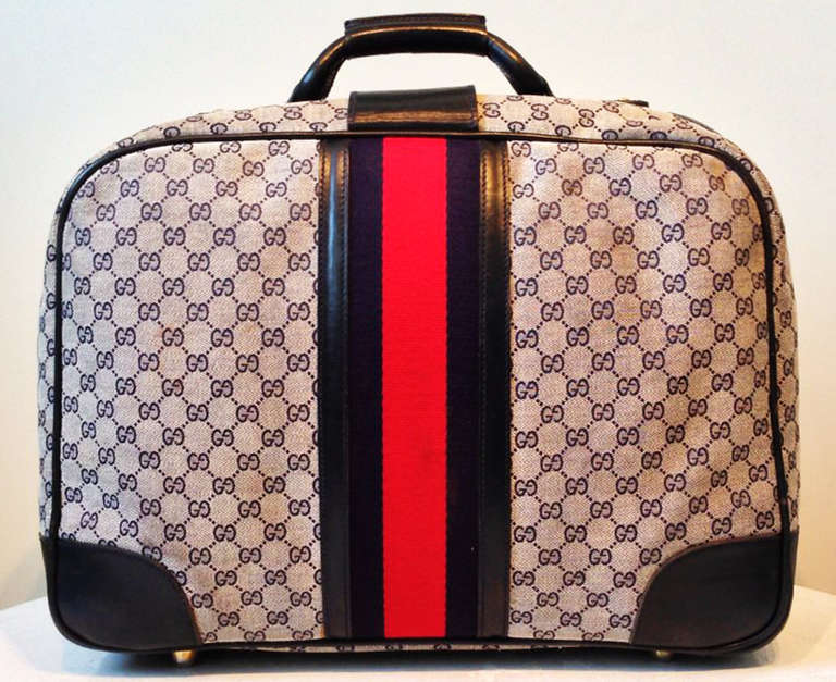 A fine vintage Gucci suitcase. Iconic woven canvas item features navy blue leather and classic blue/red canvas center trim. Original brass buckle and glides intact.