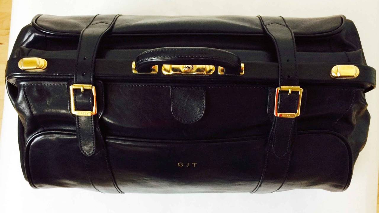 A exquisite vintage Bally gent's valise suitcase. Signed highly polished black leather item features gilt metal hardware, locks and glides. Leather covered frame opens to reveal a pristine linen interior. Original keys and signature dust cover