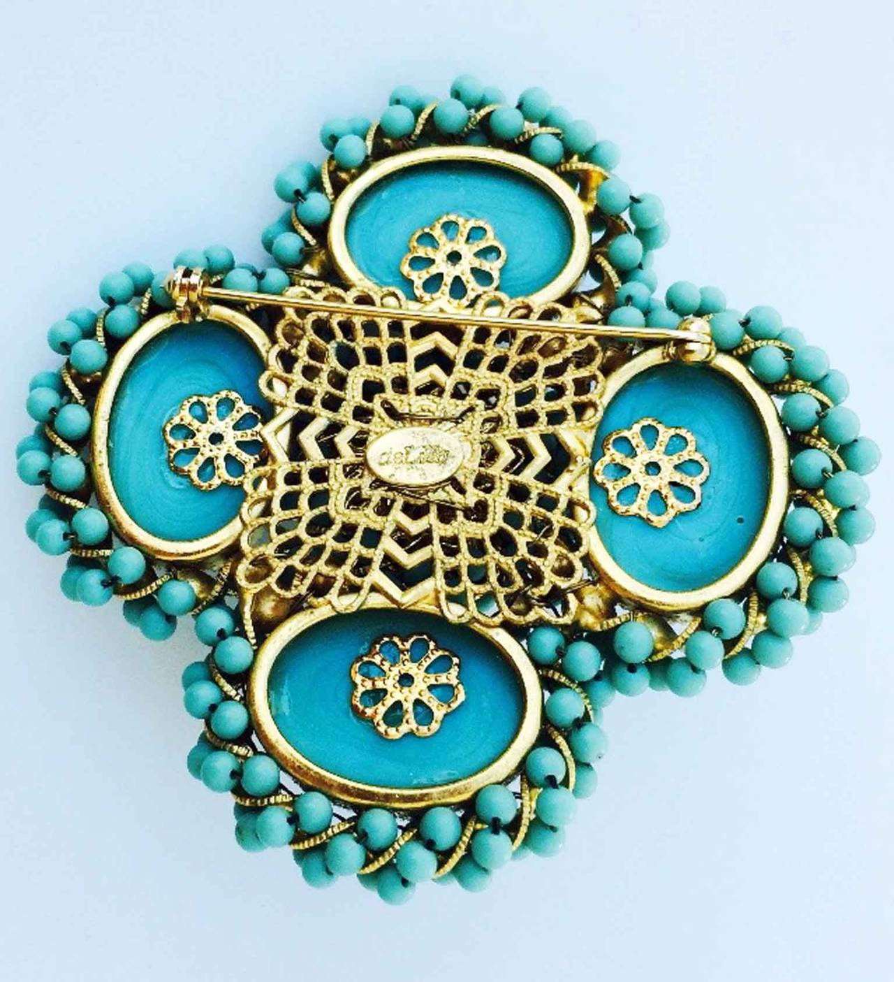 A fine vintage William de Lillo sample brooch dating to 1970. Signed gilt metal item features faux Persian turquoise beads and matching bezel set cabochon centers. Sample item from the Wm. de Lillo archives. Matching clip back earrings available.