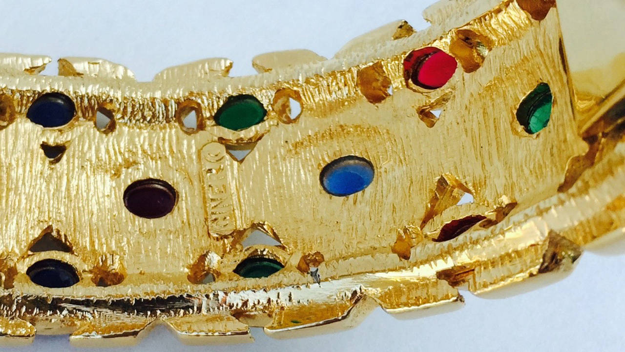 A fine vintage Ciner enamel cuff bracelet. Signed gilt metal item in the manner of David Webb features ivory enamel and tri-color glass cabochons (faux emerald, sapphire and ruby). Hinged item retains hidden push clasp locking closure. Pristine