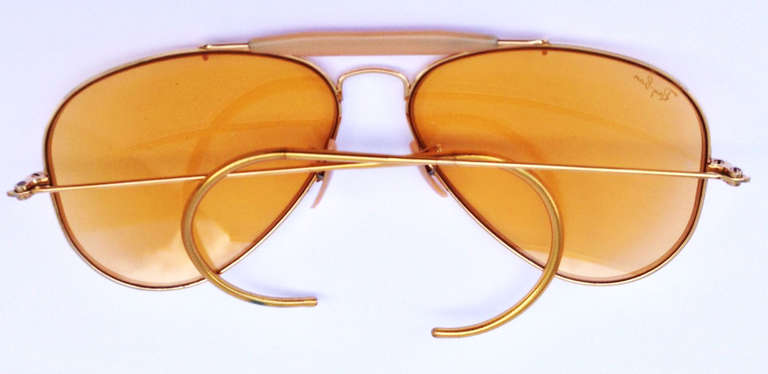 A fine vintage pair Ray Ban aviator sunglasses. Gilt gold wire frames feature original Bausch and Lomb yellow glass lenses and plastic guards. Signature leather case intact and included.
