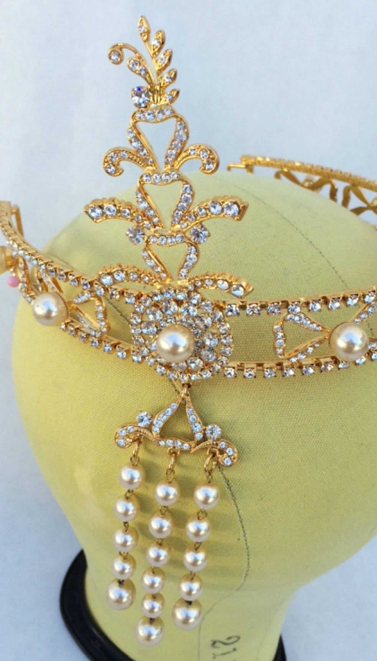A fine and rare vintage diadem headband. Engraved gilt metal item features prong set crystals and faux pearl centers and pendant. Excellent.