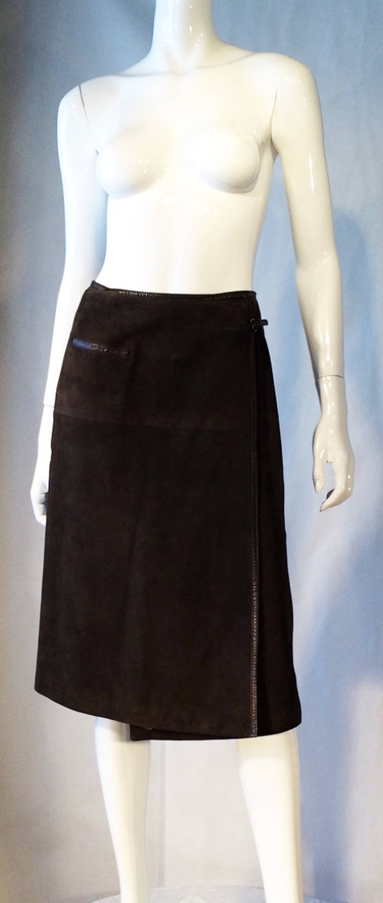 A fine vintage Hermes suede leather wrap skirt. Dark olive dyed suede leather item trimmed in a matching saddle leather trim. Item fully lined and hooks and belts wrap closures. Excellent.