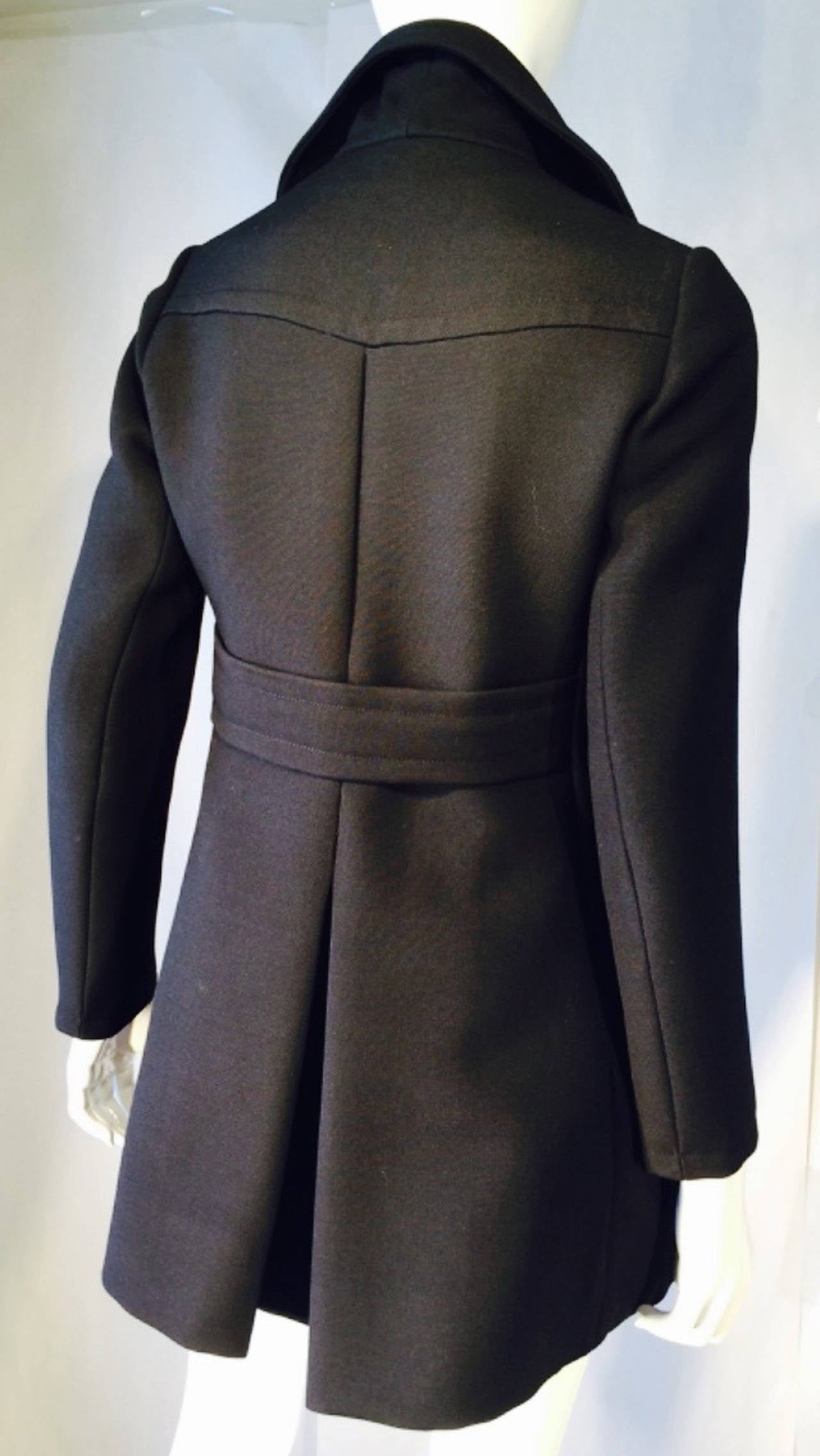 A fine and rare vintage Pierre Balmain pea coat. Authentic jet-black woven wool item features hand construction, precision seams, side pockets and large notched collar. Attached back half belt secures generous back center pleats. Pristine appears